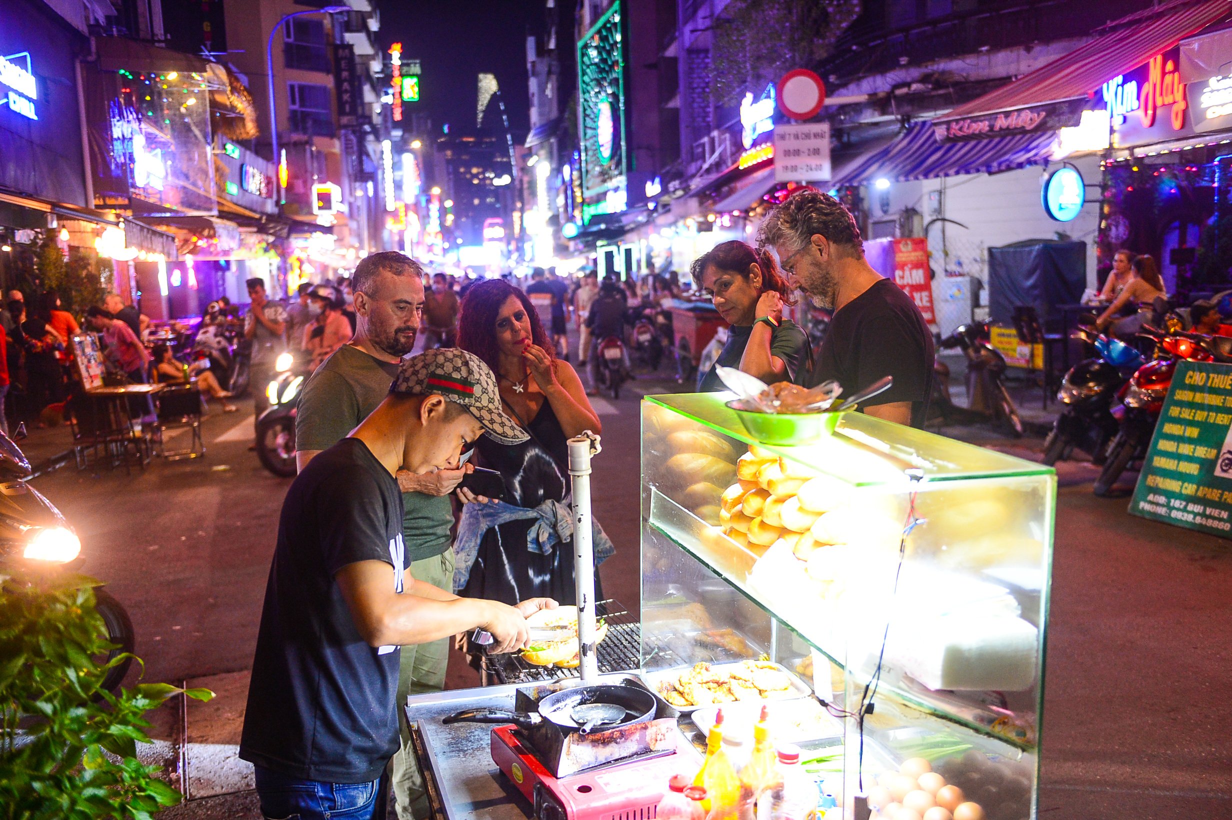 <em>A file photo shows foreign tourists buying 'banh mi' at a street stall in Ho Chi Minh City. Photo: </em>Quang Dinh / Tuoi Tre