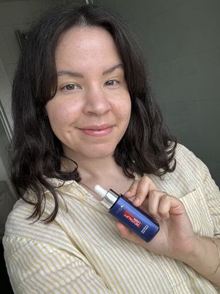 A picture of mica holding a bottle of L'Oréal Paris Pure Retinol Revitalift Laser Night Serum